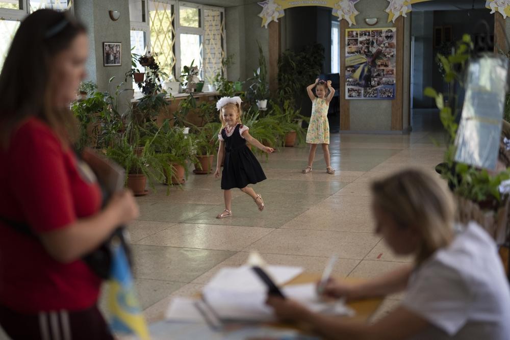 Girls play as a woman distributes iodine tablets to residents at a local school in case of a radiation leak in Zaporizhzhia, Ukraine, Friday, Sept. 2, 2022. Heavy fighting continued Friday near Europe's largest nuclear power plant in a Russian-controlled area of eastern Ukraine, a day after experts from the U.N.'s nuclear watchdog agency voiced concerns about structural damage to the sprawling Zaporizhzhia site. (AP Photo/Leo Correa)